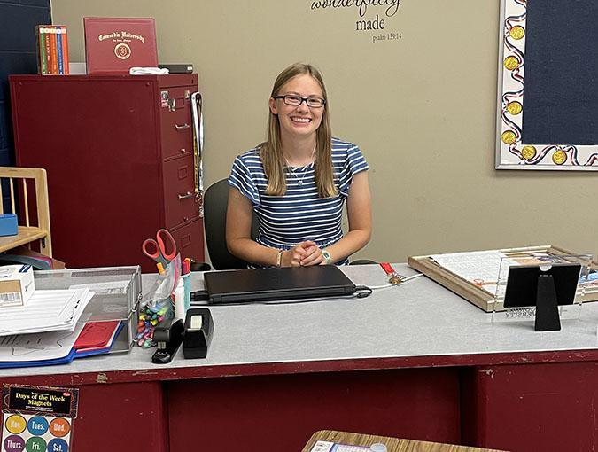 Charity Felton sitting behind a desk and smiling at the camera